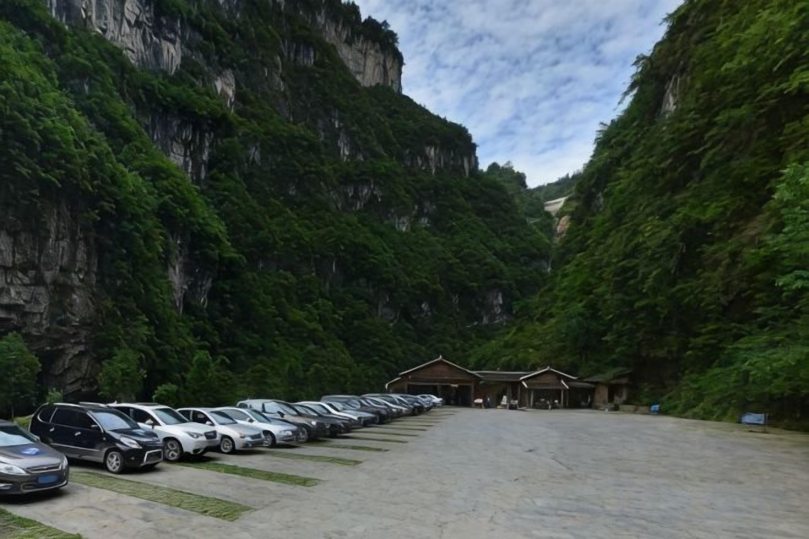 A parking lot with cars, a building with a sloped roof, and a mountainous backdrop.