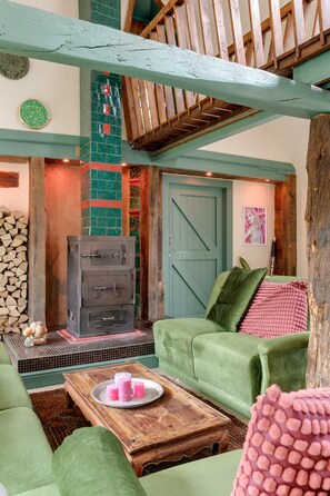 A cozy living room with a fireplace, green upholstered furniture, and a rustic wooden ceiling. - Summer house retreat in the garden – 10 guests, every room ensuite (Kockengen)