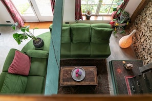 A cozy room with a green sofa, a wooden coffee table, and a variety of plants.