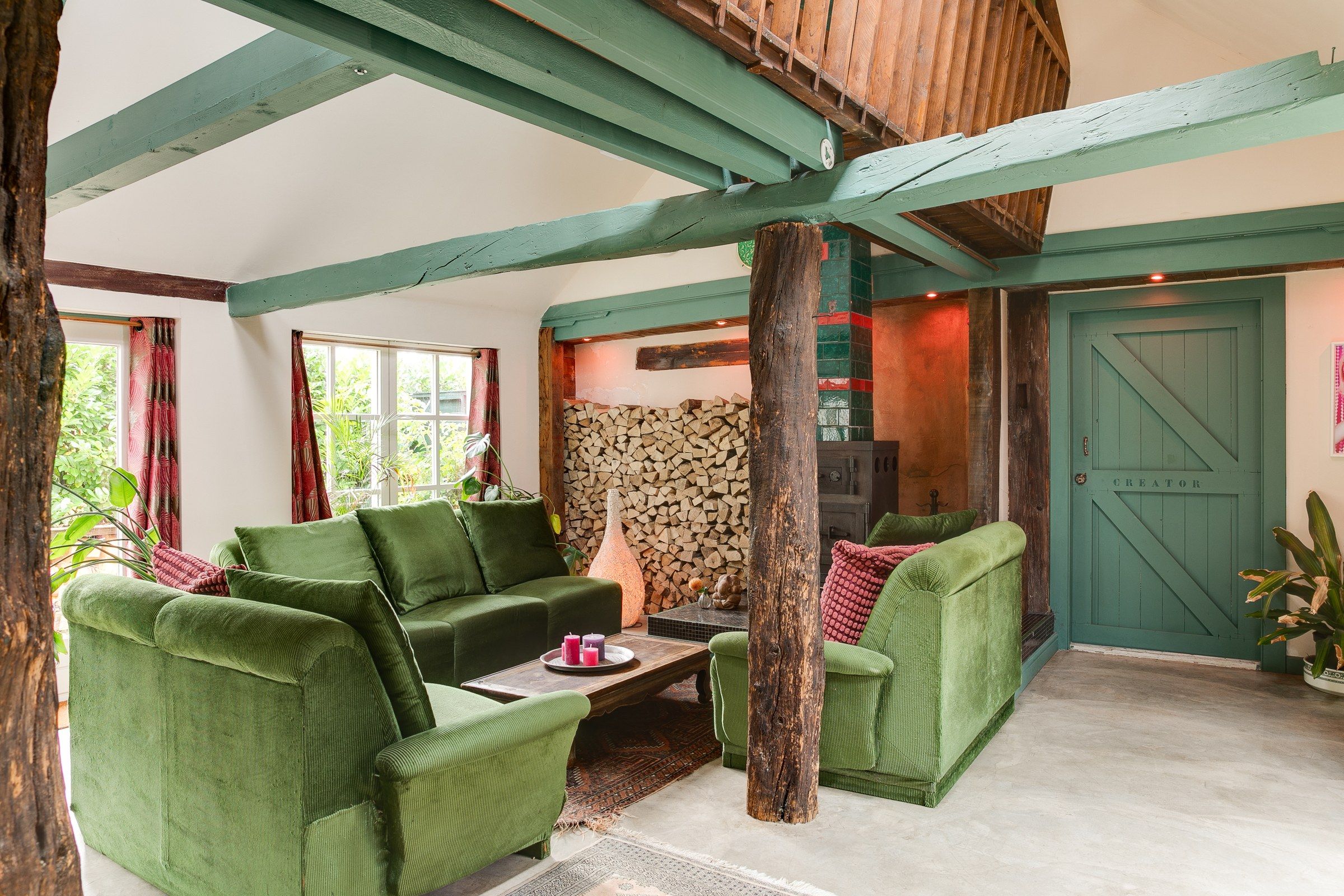 A cozy living room with green furniture, a fireplace, and a door labeled 'REATOR'.