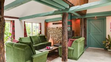 A cozy living room with green furniture, a fireplace, and a door labeled 'REATOR'.