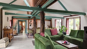 A spacious living area with green upholstered furniture, a wooden coffee table, and a high ceiling with exposed beams. - BoHo Experience - Jacuzzi, Sauna, BBQ, Garden, close to Amsterdam - Sleeps 10 (Kockengen)