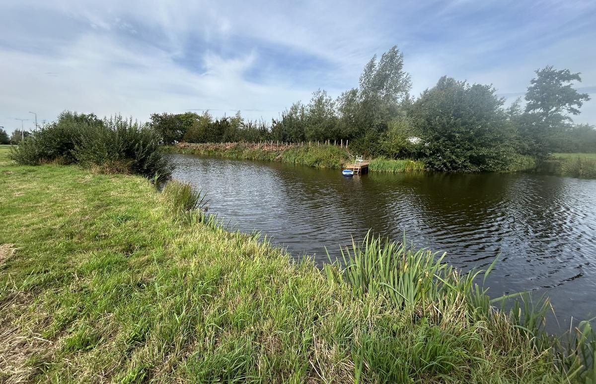 A calm river with a small boat, surrounded by lush greenery and trees.