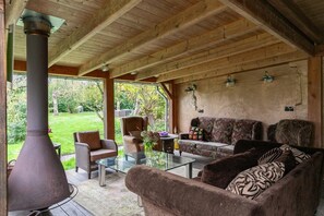A cozy living room with a fireplace, comfortable seating, and a view of the outdoors. - Summer house retreat in the garden – 10 guests, every room ensuite (Kockengen)