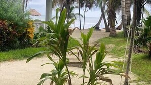 A beachside view with a white building, palm trees, and a sandy path leading to the beach. - 20 Steps From The Beach @ Sapphire Beach Resort (San Pedro Town)