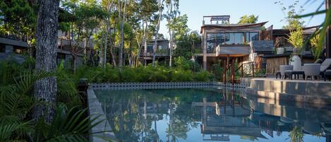 Un resort moderno con una piscina central rodeada de exuberante vegetación y árboles.
