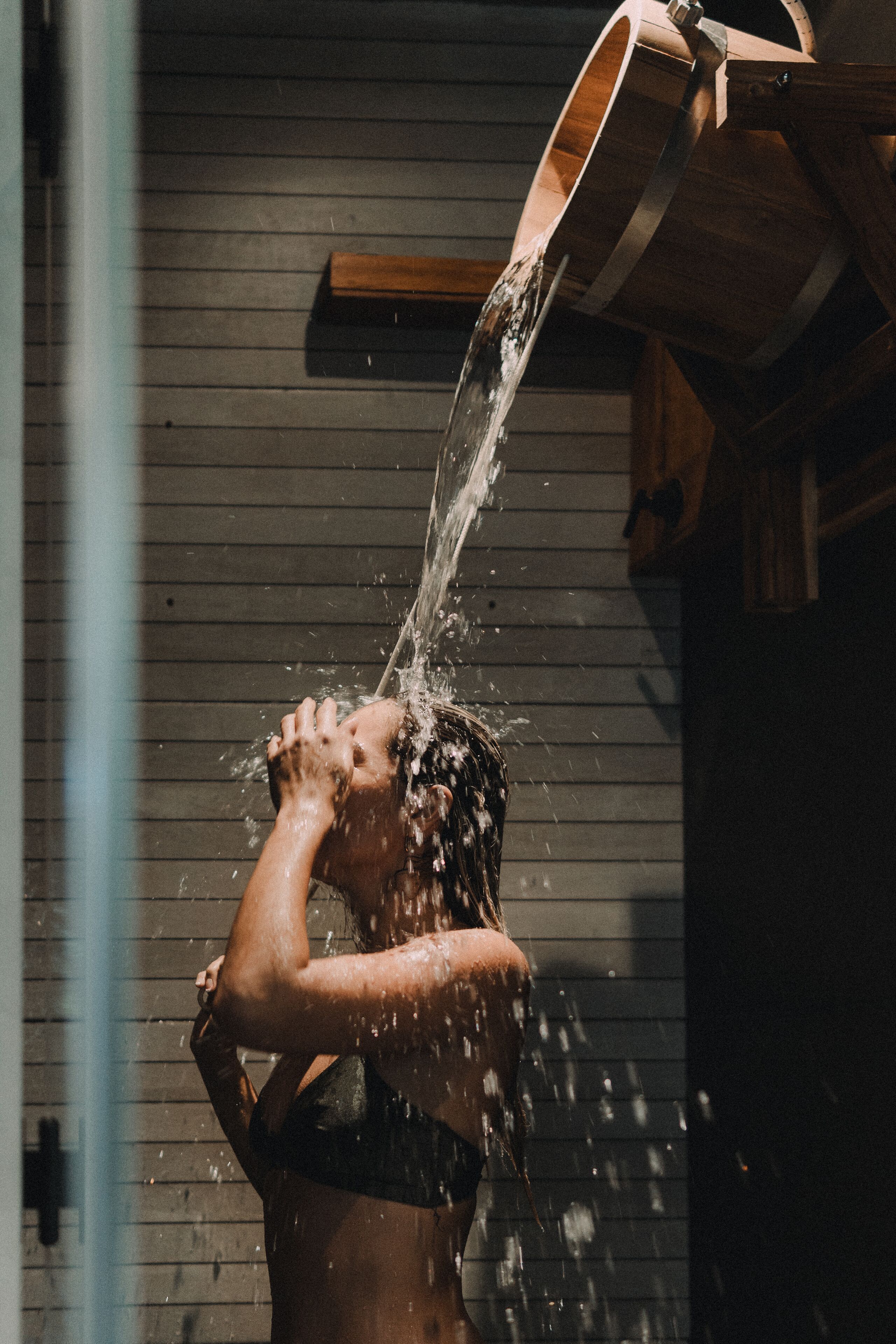Una persona bebiendo agua de un caño de madera.