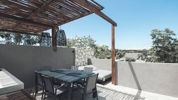 An outdoor patio with a table and chairs, a stone wall, and a pergola.