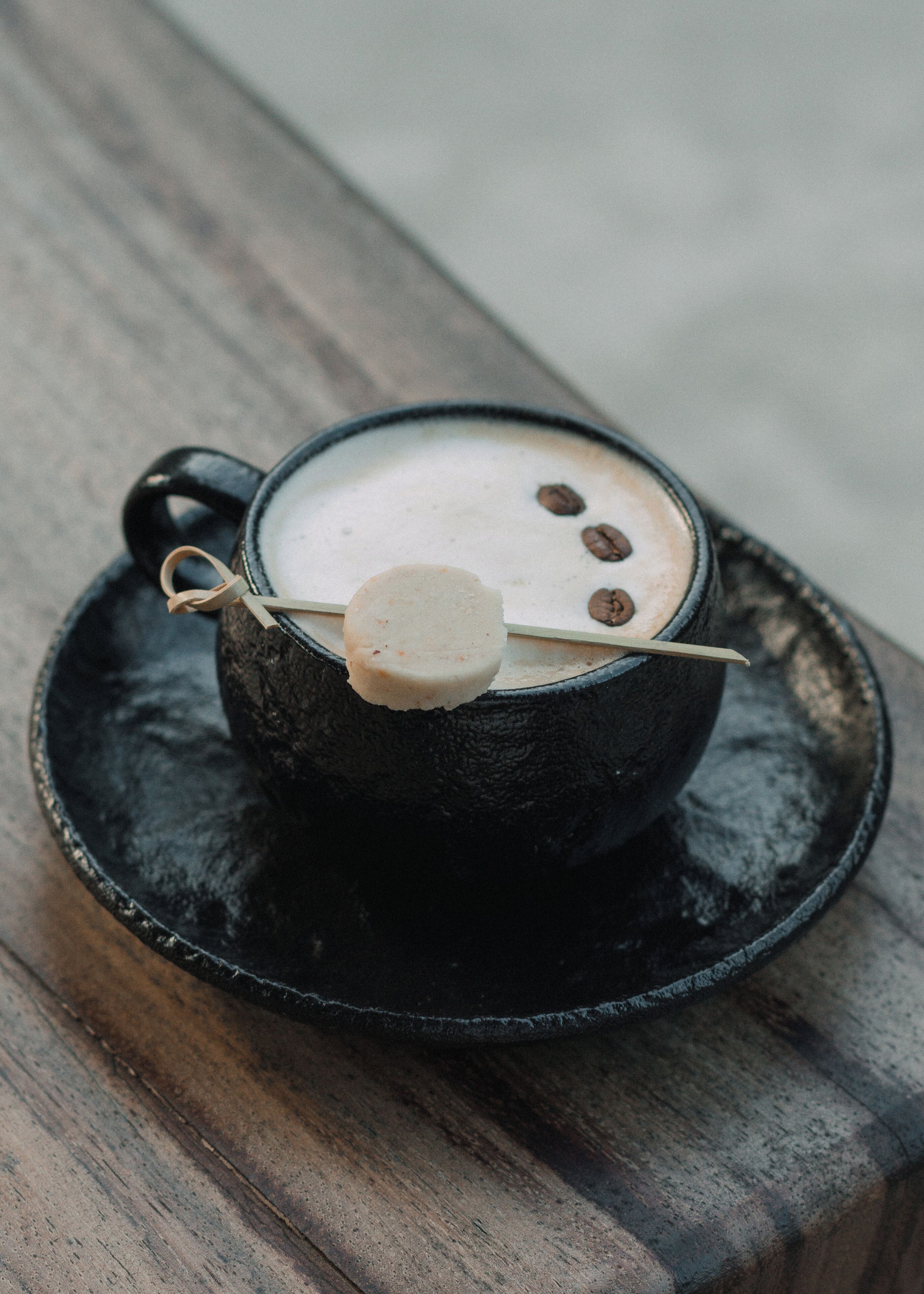 A cup of coffee with a biscotti on a saucer.