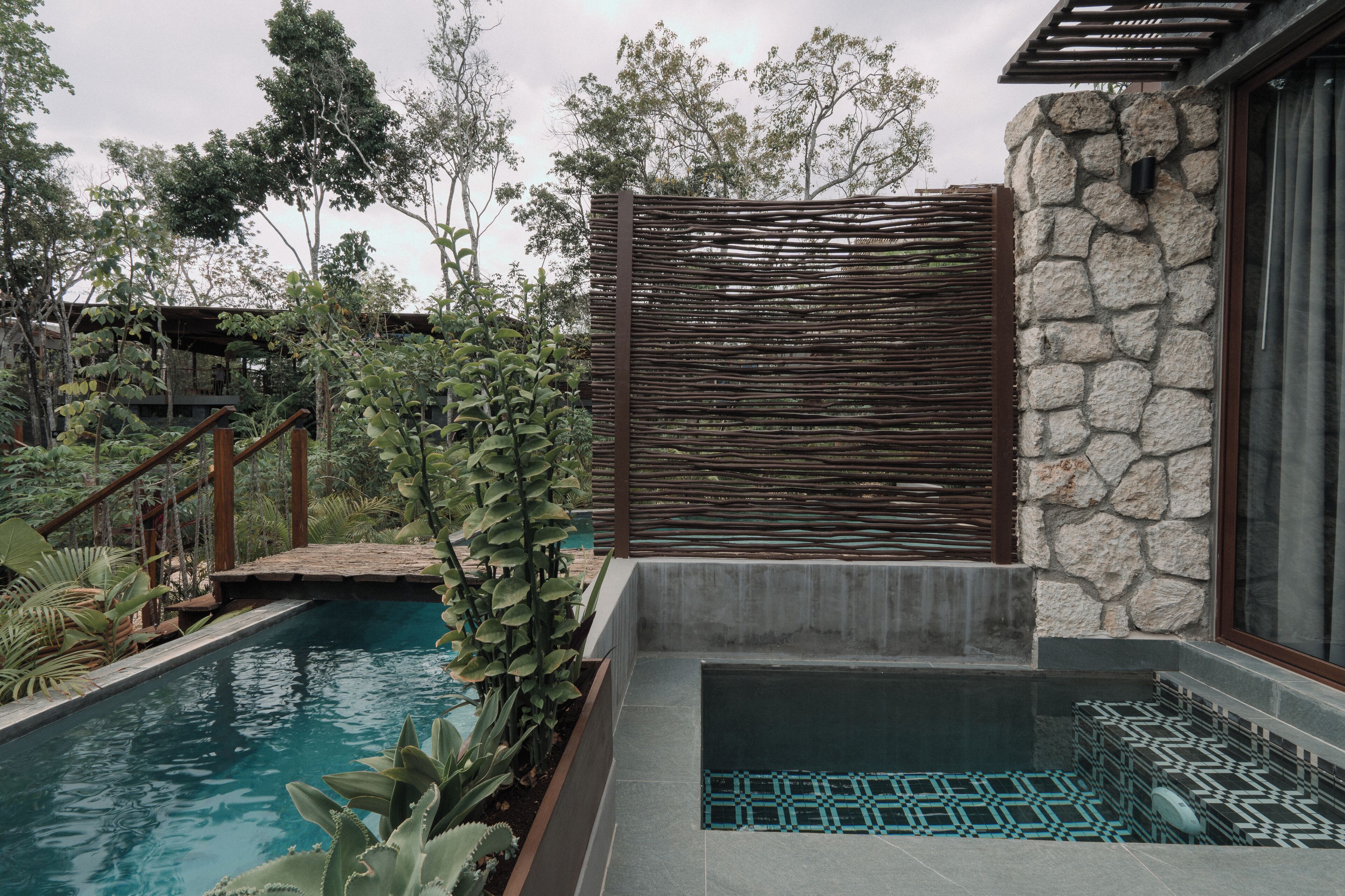 A swimming pool with a stone wall and a wooden fence.
