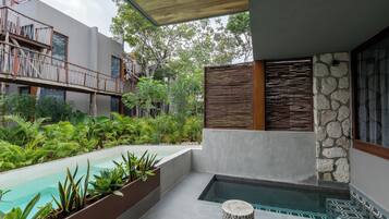A modern outdoor pool area with a built-in jacuzzi, surrounded by lush greenery and a wooden deck.
