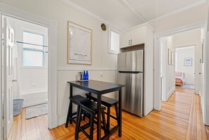 Enjoy cooking in this well-equipped kitchen with a refrigerator, cabinetry, and a wooden floor.