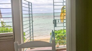 A room with a view of the ocean, a chair, and a table with a patterned tablecloth. - Walk out to Sugar beach (Christiansted)