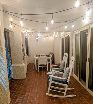 A patio with a table and chairs, string lights overhead, and a sliding glass door. - Walk out to Sugar beach (Christiansted)