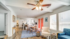 A spacious living area with a ceiling fan, a dining table with chairs, a sofa, and a kitchen in the background. - Charleston Home w/ Porch - 3 Mi to Folly Beach! (Charleston)