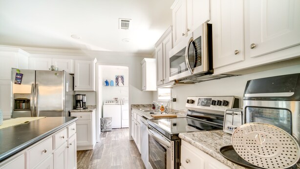 A modern kitchen with white cabinets, stainless steel appliances, and a marble countertop. - Charleston Home w/ Porch - 3 Mi to Folly Beach! (Charleston)