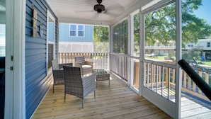 A covered porch with wicker furniture, a ceiling fan, and large windows offering a view of the neighborhood. - Charleston Home w/ Porch - 3 Mi to Folly Beach! (Charleston)