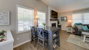 A spacious living room with a fireplace, a dining area with a table and chairs, and a cozy seating area with a couch and a side table. - Lovely Morehead City Home w/ Fire Pit & Gas Grill (Morehead City)