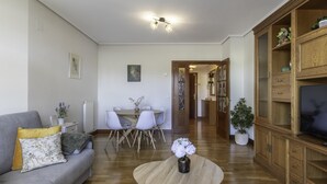 Un salon avec un canapé gris, une table basse ronde et un coin repas comprenant une table et des chaises blanches.