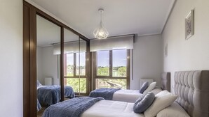 Une chambre avec deux lits, un grand miroir et une vue sur la verdure.