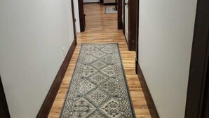 A narrow hallway with wooden flooring and a patterned rug. - Family Home in Carthage (Carthage)
