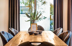 Ein Holztisch mit vier Stühlen, eine Vase mit einer Pflanze und ein Menüständer.