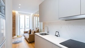 Une cuisine moderne équipée d’une cuisinière intégrée, d’un évier et d’un coin repas comprenant un canapé et une petite table ronde.