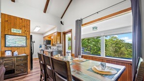 A dining area with a wooden table, chairs, and a view of the outdoors.