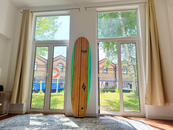 Enjoy a view of the surrounding area from the large window in this room, which features a carpeted floor and a convenient surfboard propped against the wall.
