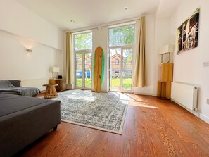 Relax in this stylish room with a sofa, table, and floor-to-ceiling radiator, leading to an outdoor area.
