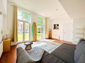Relax in this stylish living room with a large sofa, wooden surfboard, and comfortable stool.