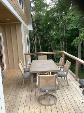 A wooden deck with a table and chairs, surrounded by trees.