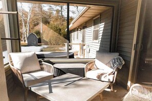 Ein überdachter Außenbereich mit Stühlen und einem Tisch, mit Blick auf ein Haus und einen Garten.