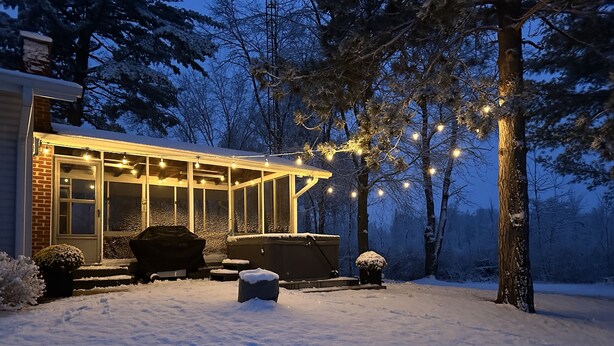 A snow-covered patio area with a hot tub, outdoor seating, and string lights. - Private, newly renovated lakefront cottage on 10+ acres of land. (Brooklyn)