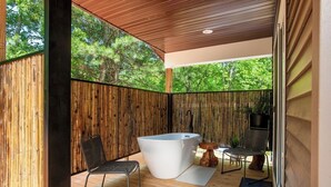 Een modern buitenzwembadgedeelte met een houten terras, een zwarte metalen stoel en een witte jacuzzi.