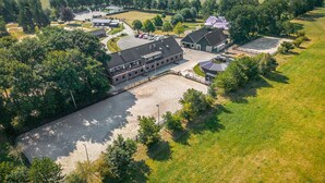 Luchtbeeld van een groot landgoed met meerdere gebouwen, waaronder een hoofdgebouw, gastenverblijven en een stal.