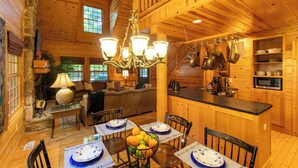 A wooden cabin interior with a dining area, kitchen, and living space.
