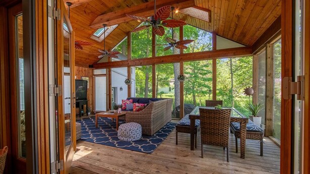 A spacious room with a wooden ceiling, large windows, a sofa, chairs, and a table. - Saugatuck Cottage Steps from Downtown! (Saugatuck)