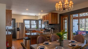 A modern kitchen with stainless steel appliances, wooden cabinets, and a large island. - Saugatuck Cottage Steps from Downtown! (Saugatuck)