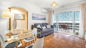 A modern living room with a glass dining table, grey sofa, and a balcony with a view. - Lovely apartment in Campello (Campello)