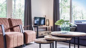 Uma sala de estar moderna com sofá, TV e uma pequena mesa com uma planta.