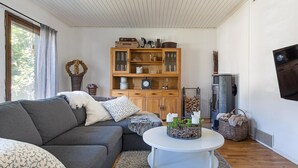 Un accogliente soggiorno con un divano grigio, un tavolino da caffè bianco e un mobile in legno con ante in vetro.