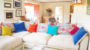 A living room with a white sofa adorned with colorful pillows, a glass coffee table with magazines, and framed artwork on the walls. - Stunning country house (Bix, outside Henley) (Henley)