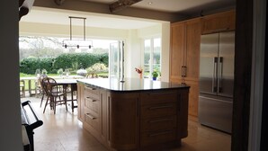 A spacious kitchen with a large island, wooden cabinets, and a stainless steel refrigerator. - Stunning country house (Bix, outside Henley) (Henley)