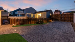 A residential neighborhood with houses, a wooden fence, and a paved driveway. - THE Unique Belmar Stay | Prime Location. Privacy. 9 Badges. 2 Grills. Fire Pit. (Belmar)