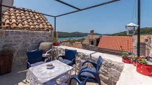A terrace with stone walls, red-tiled roofs, and a view of a coastal town. - Awesome home in Kaprije with WiFi (Kaprije)