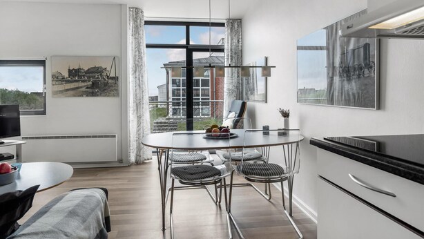 A modern kitchen with a dining area, large windows, and artwork on the walls. - Beautiful apartment in Fanø with WiFi (Fanø)