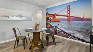 Ein Essbereich mit einem Tisch für vier Personen, einem Wandgemälde der Golden Gate Bridge und einer modernen Deckenleuchte.