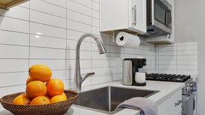 Eine moderne Küche mit Spüle aus Edelstahl, einer Kaffeemaschine und einer Korb voller Orangen.