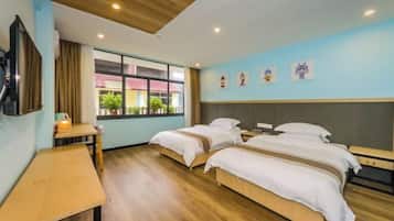 A hotel room with two beds, a desk, a window with a view, and a ceiling with recessed lighting.